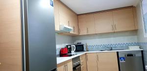 cocina con armarios de madera y nevera de acero inoxidable en Apartamento Torrevieja, en Torrevieja