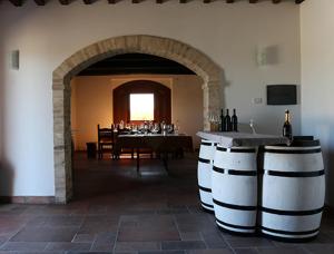 une salle à manger avec une table et des tonneaux de vin dans l'établissement Casale Rialto, à Montefalco