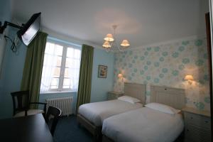 Una habitación de hotel con dos camas y una ventana. en Auberge du Cabestan Hotel Audierne, en Audierne