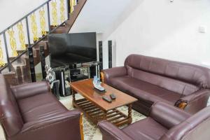 a living room with leather couches and a television at Prince Villa Sigiriya in Sigiriya