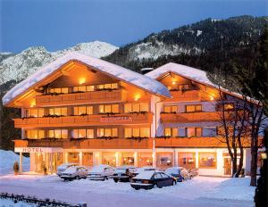 ein großes Gebäude im Schnee mit vor der Tür geparkt in der Unterkunft Hotel Brunella in Vandans