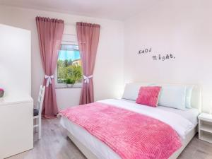 Un dormitorio con una cama con una manta rosa. en Apartment in Croatia with Sea Views, en Dramalj