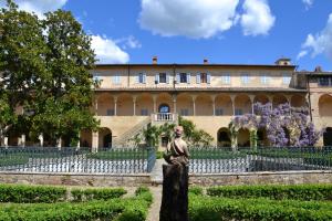 un edificio con una statua di fronte a un giardino di Certosa di Pontignano Residenza d'Epoca a Ponte A Bozzone
