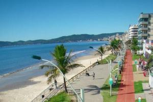 una playa con palmeras y gente caminando sobre ella en Apartamento em Meia Praia, Itapema, SC., en Itapema