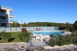 a swimming pool with two lounge chairs in front of a building at Apartmani Uwe in Banjole