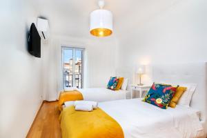 a white bedroom with two beds and a tv at WHome | Casino Premium Apartment in Lisbon