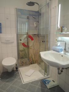 a bathroom with a shower and a toilet and a sink at Hotel Ostfriesland garni in Norden