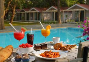 a table with plates of food and drinks next to a pool at Blu Resorts in Vagator