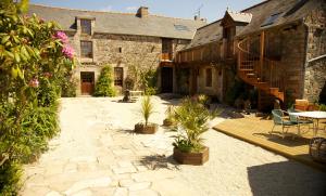 un patio de un edificio de piedra con mesa y sillas en Gîtes Saint Aubin, en Erquy