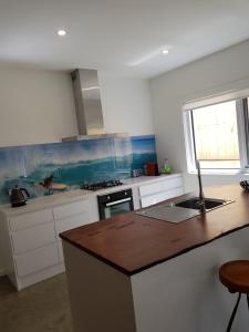 a kitchen with white cabinets and a wooden counter top at Zeally Bay Stay Deep Ocean in Torquay