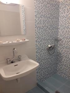 W łazience znajduje się umywalka oraz prysznic z lustrem. w obiekcie Hermes w miejscowości Agia Marina