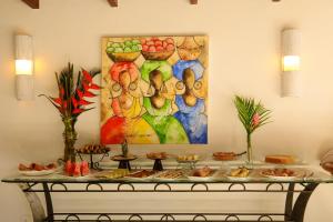 a table with food on it with a painting on the wall at Pousada Coisa e Tao in Arraial d'Ajuda