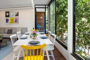 une salle à manger avec une table blanche et des chaises jaunes dans l'établissement The Ascension in Druyanov by HolyGuest, à Tel Aviv