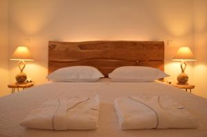 a bedroom with a bed with white sheets and two lamps at Small Paradise in Andros