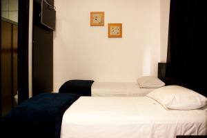 two beds in a room with white sheets and pillows at Bras Palace Hotel in Sao Paulo