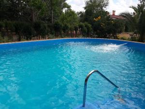 a large blue swimming pool with a metal hand rail at Agroturismo la finka in Los Quiles