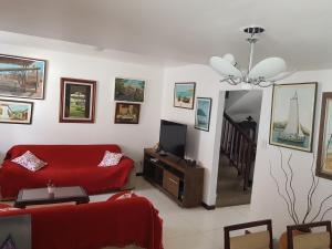 a living room with a red couch and a television at Casa 4/4(Amplos), Cond. fechado com piscina-150m2 in Salvador