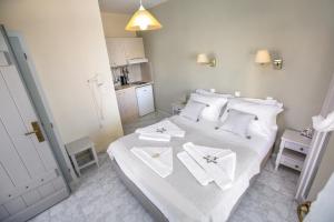 um quarto com uma cama branca e toalhas em Alexandra's Rooms em Parikia
