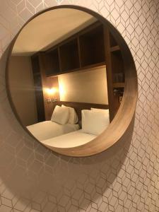 espejo que refleja un dormitorio con cama con almohadas blancas en The Enniskillen Hotel and Motel en Enniskillen