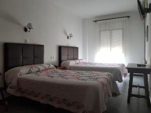 - une chambre avec 2 lits, une table et une fenêtre dans l'établissement Hotel La Noria, à Lepe