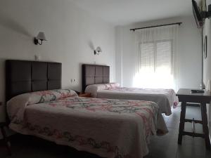 a bedroom with two beds and a table and a window at Hotel La Noria in Lepe