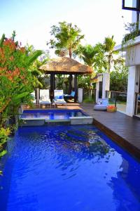 a swimming pool with blue water in front of a house at Indah Balangan Villa in Jimbaran