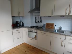 a kitchen with white cabinets and a stove top oven at Hiltje - Nice to stay in Dordrecht