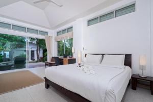 a bedroom with a white bed and a large window at Ban Mok Talay Beachfront Villa in Bang Rak Beach