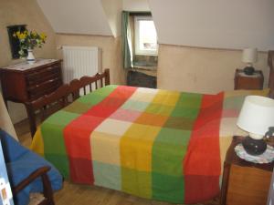Un dormitorio con una cama colorida y una mesa con una lámpara. en Gites du ROHERAN, en Malansac 7 fotos más