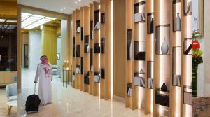 a woman with a suitcase walking through a lobby at Boudl Al Olaya in Riyadh