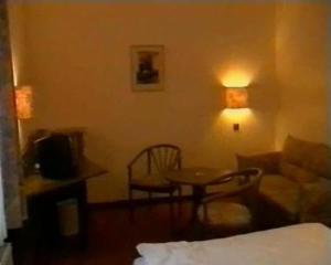 ツヴィッカウにあるホテル メルクル ガーニのベッド、テーブル、ソファが備わる客室です。