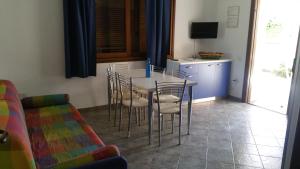 una sala da pranzo con tavolo, sedie e TV di Villa Simius a Villasimius