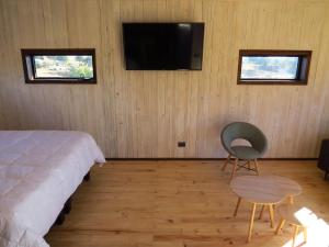 een slaapkamer met een bed, een stoel en een televisie bij Punta Sal Pichilemu in Pichilemu