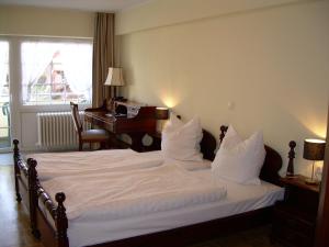 ein Schlafzimmer mit einem Bett mit weißer Bettwäsche und einem Klavier in der Unterkunft Hotel-Restaurant Sälzerhof in Salzkotten