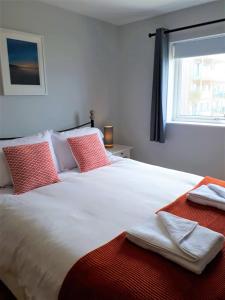 a bedroom with a large white bed with red pillows at For the Shore, Fistral Beach Newquay - 2 Bed 2 bath - Private Parking with garage for 2 vehicles in Newquay