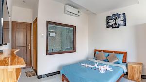 a bedroom with a bed with a blue comforter and a window at Little Boss Homestay in Hoi An