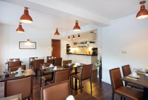 un restaurante con mesas y sillas de madera y una cocina en Conifers Guest House, en Oxford