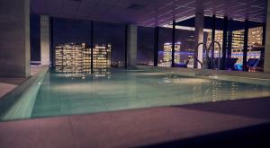 a swimming pool in a building with a city at night at Inntel Hotels Utrecht Centre in Utrecht