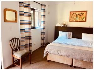 une chambre avec un lit, une chaise et un miroir dans l'établissement Garden Cottage in Ambiente Guest House, à Knysna