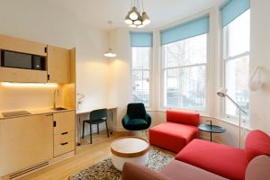 uma sala de estar com um sofá vermelho e uma cadeira vermelha em Kensington Stay em Londres