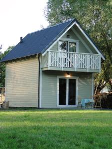 a small white house with a porch on a lawn at Jeden domek in Sztutowo