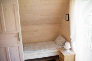 a small bed in a wooden room with a table at Jeden domek in Sztutowo