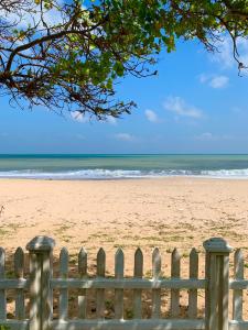 a wooden fence on a beach with the ocean at Pearl Oceanic Resort - Trincomalee in Trincomalee