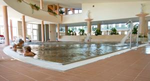 two children playing in a swimming pool in a building at Termálhotel Martfű in Martfů