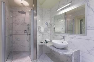 y baño blanco con lavabo y ducha. en Hotel Kristal Palace - TonelliHotels, en Riva del Garda