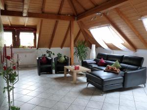 ein Wohnzimmer mit schwarzen Ledermöbeln und Fenstern in der Unterkunft Ferienwohnung Terhar in Viereth-Trunstadt