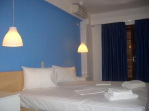 a bedroom with a white bed with a blue wall at Hotel Blue Fountain in Agia Marina Aegina