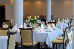 a dining room with white tables and chairs with flowers at Ambasador Centrum in Łódź