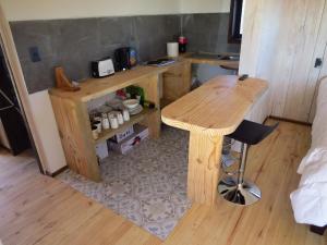 a kitchen with a wooden table and a stool at Punta Sal Pichilemu in Pichilemu