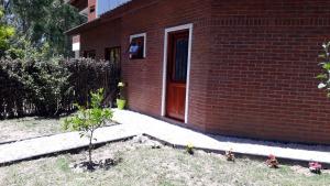 a brick house with a red door and a plant at Santa Teresita Sobre El Monte in Santa Teresita